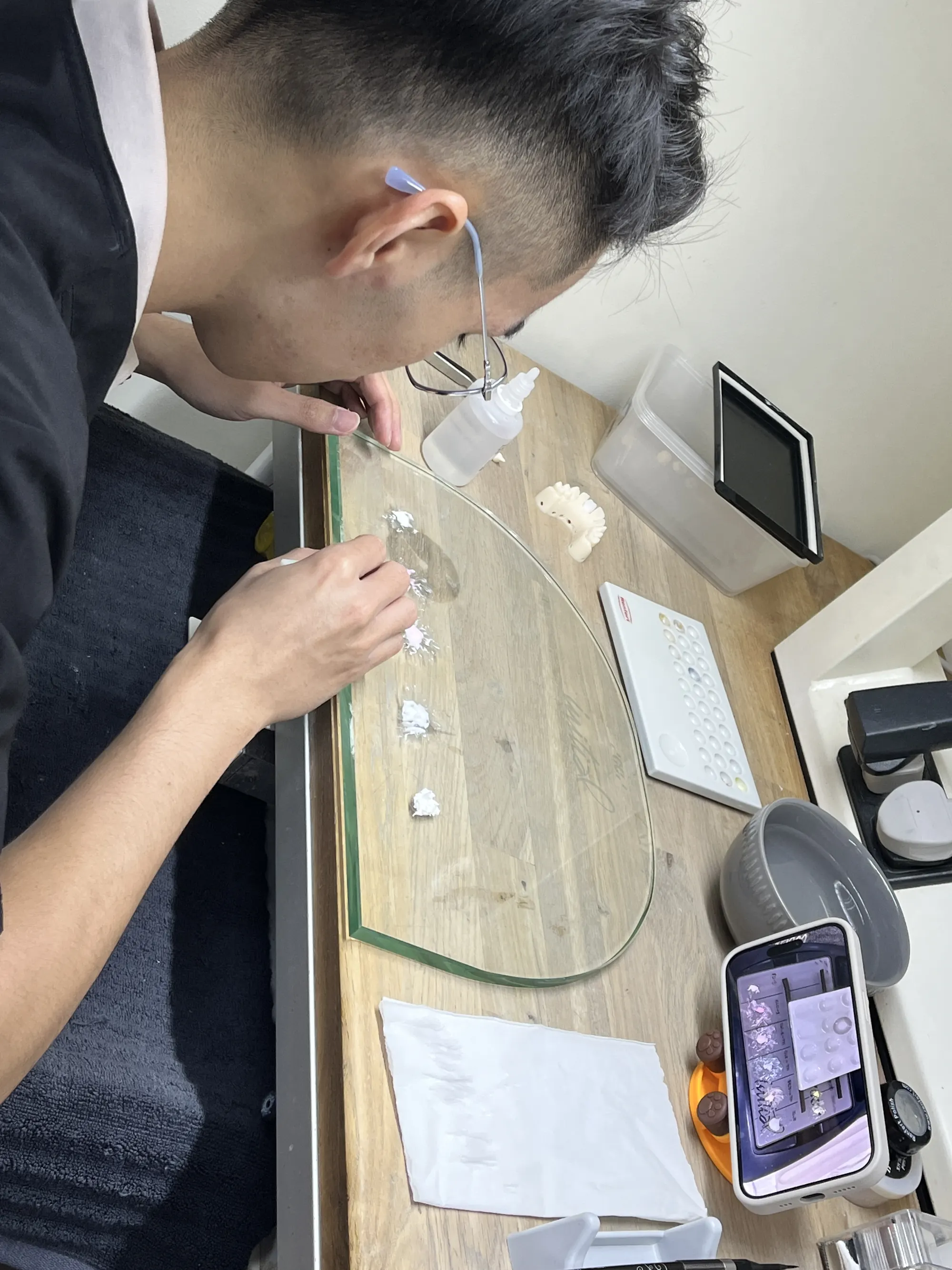 A ceramist layering porcelain under magnification at the DDA bench