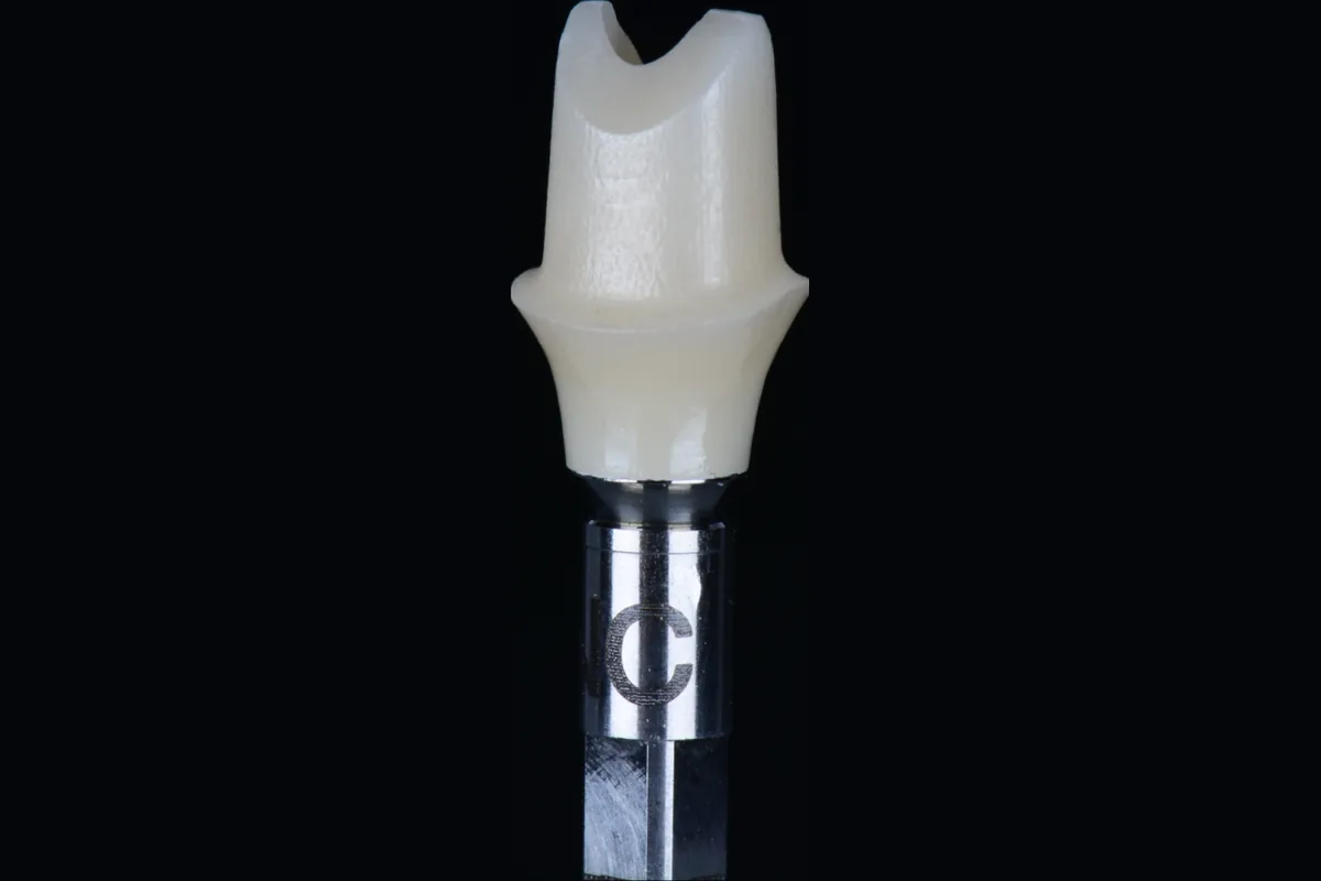 An implant crown on a holder, seen in profile
